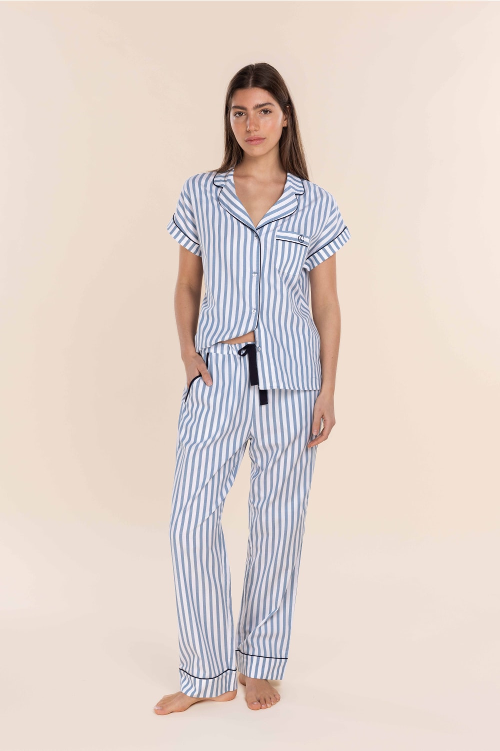 Woman wearing a blue and white striped pajama set on a beige background