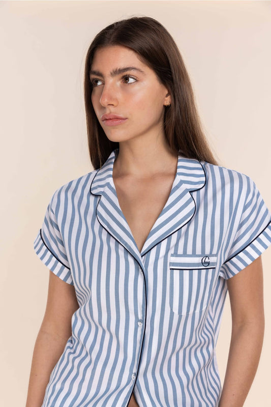 Woman wearing a blue and white striped pajama top against a beige background