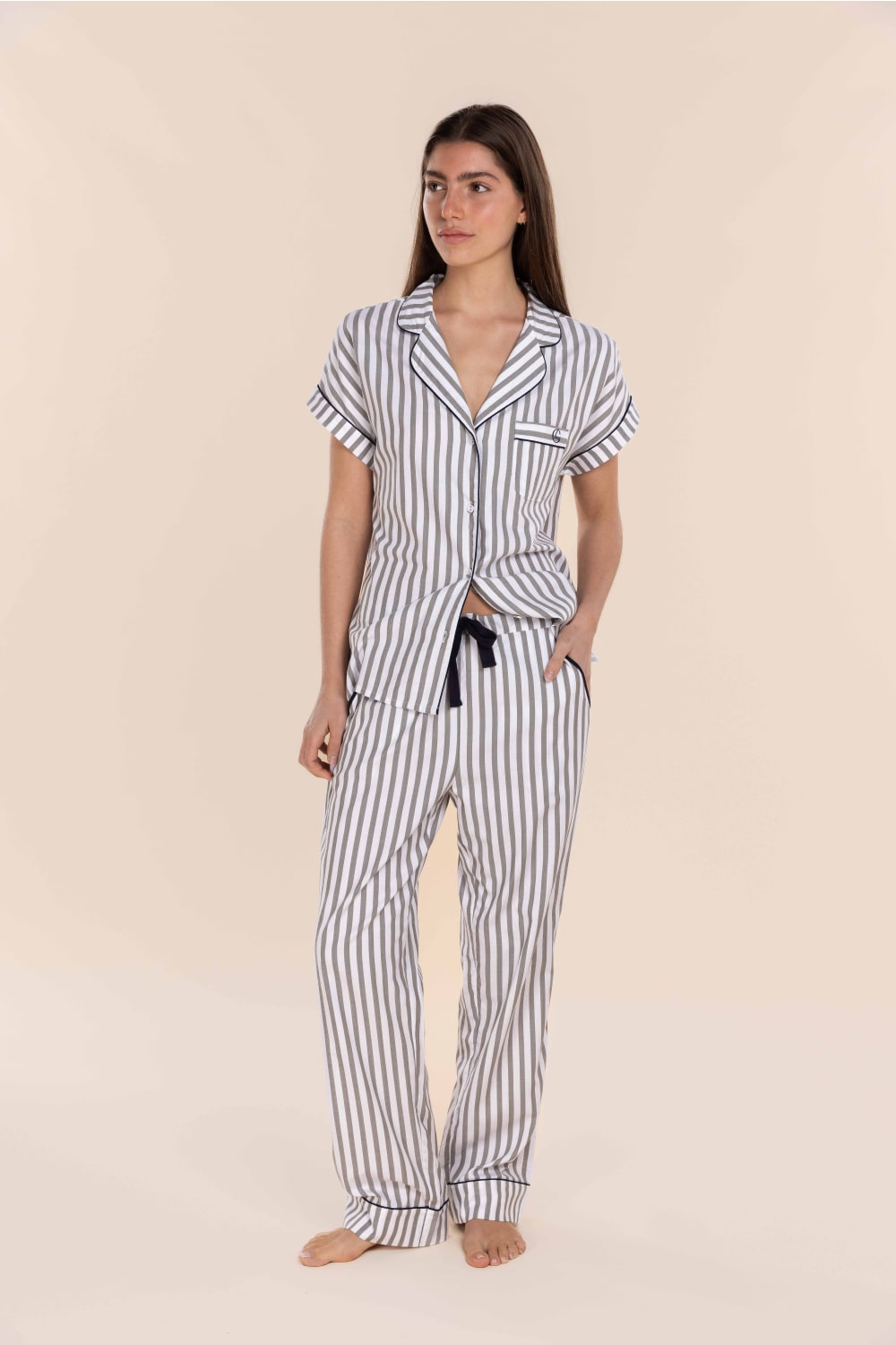 Woman wearing a striped pajama set on a beige background