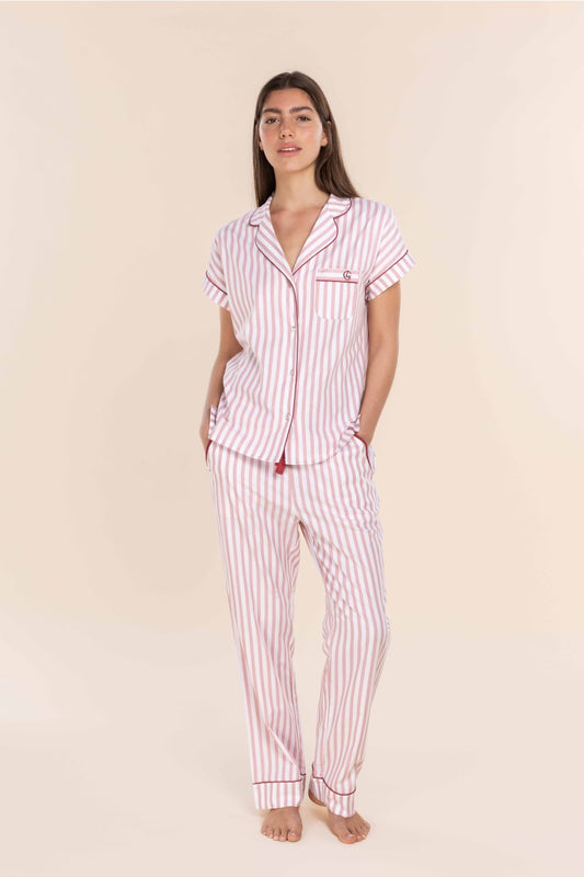 Woman wearing a red and white striped pajama set on a beige background