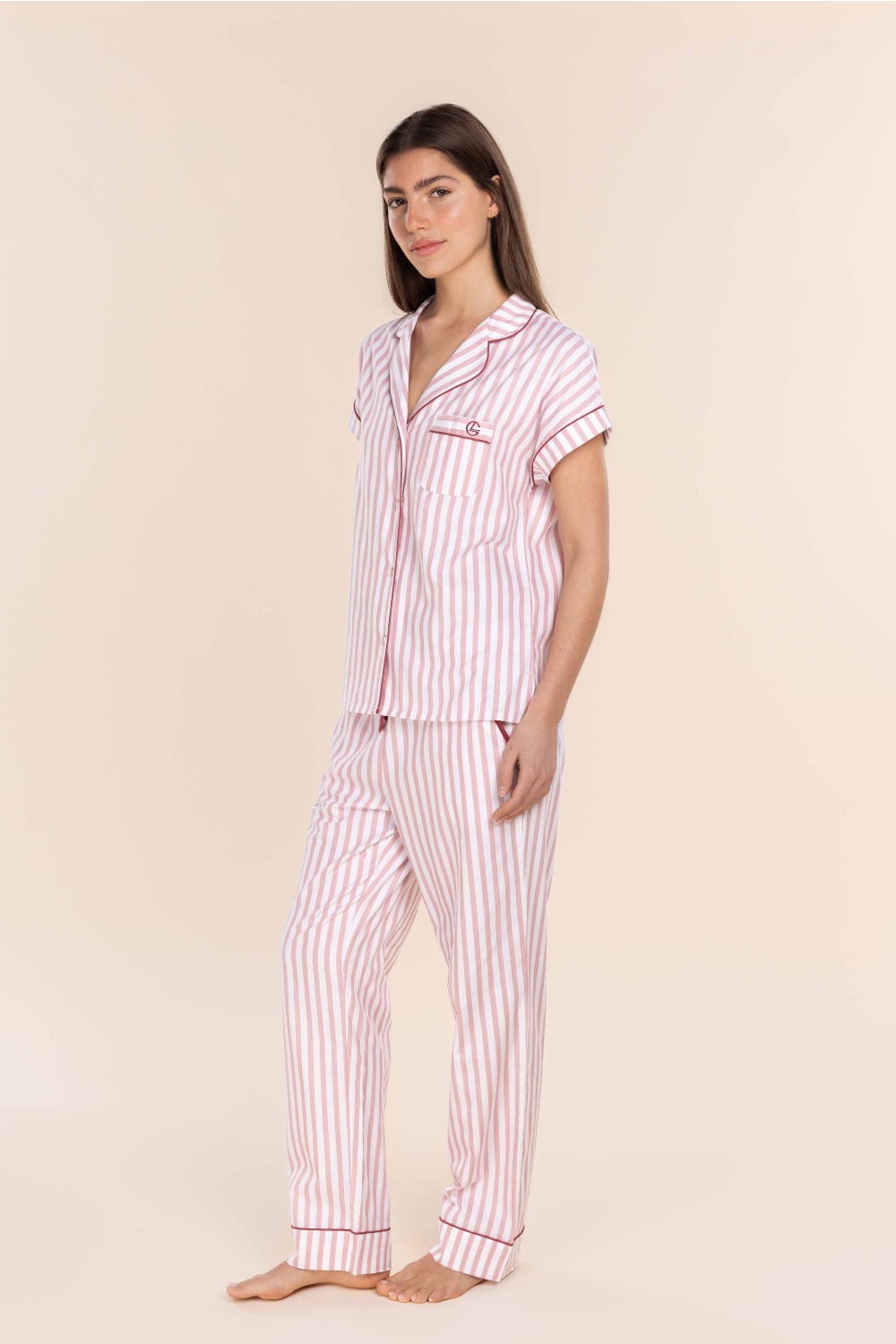 Woman wearing a pink and white striped pajama set against a beige background