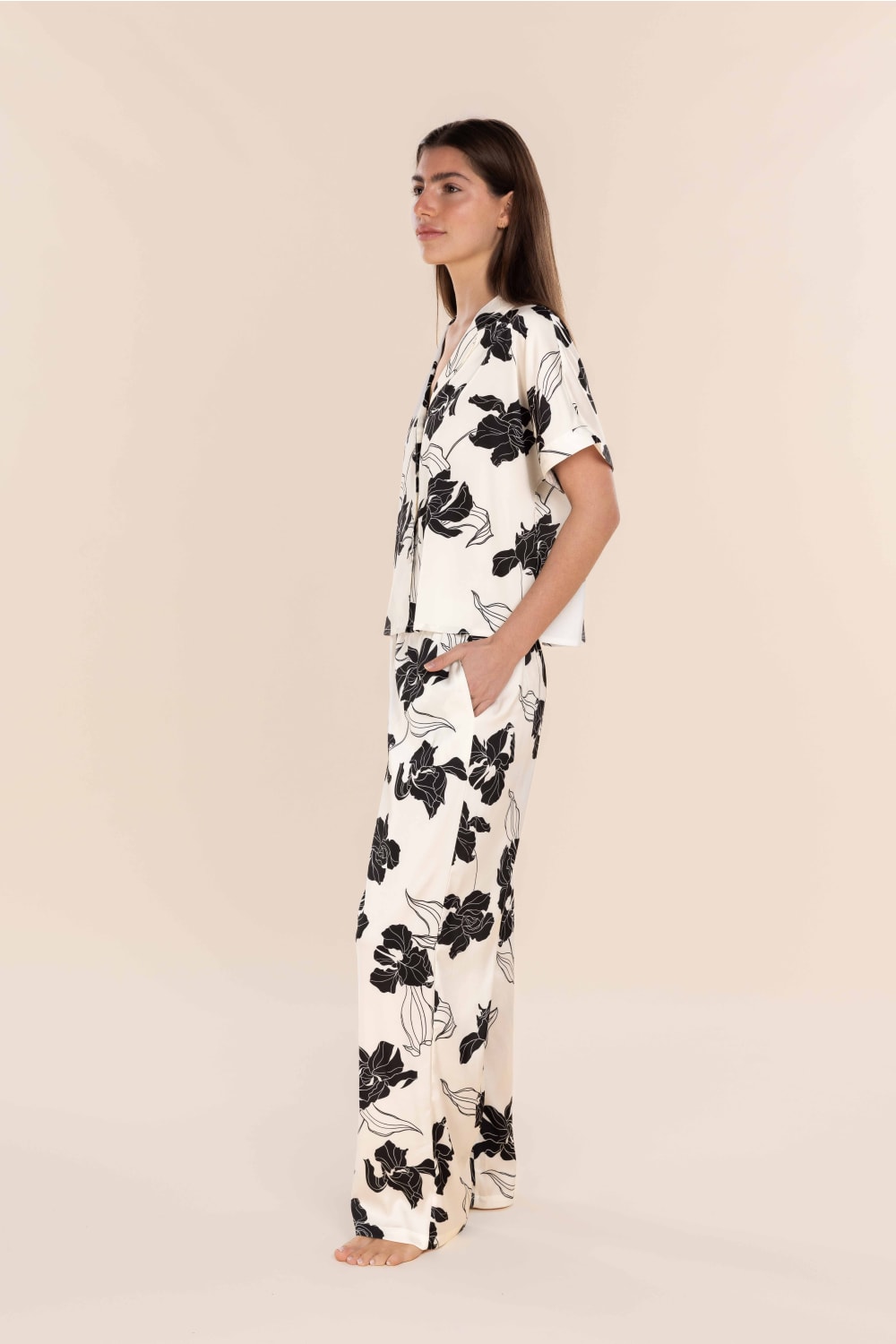 Woman wearing a black floral pajama set on a beige background