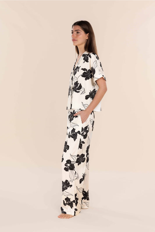 Woman wearing a black floral pajama set on a beige background
