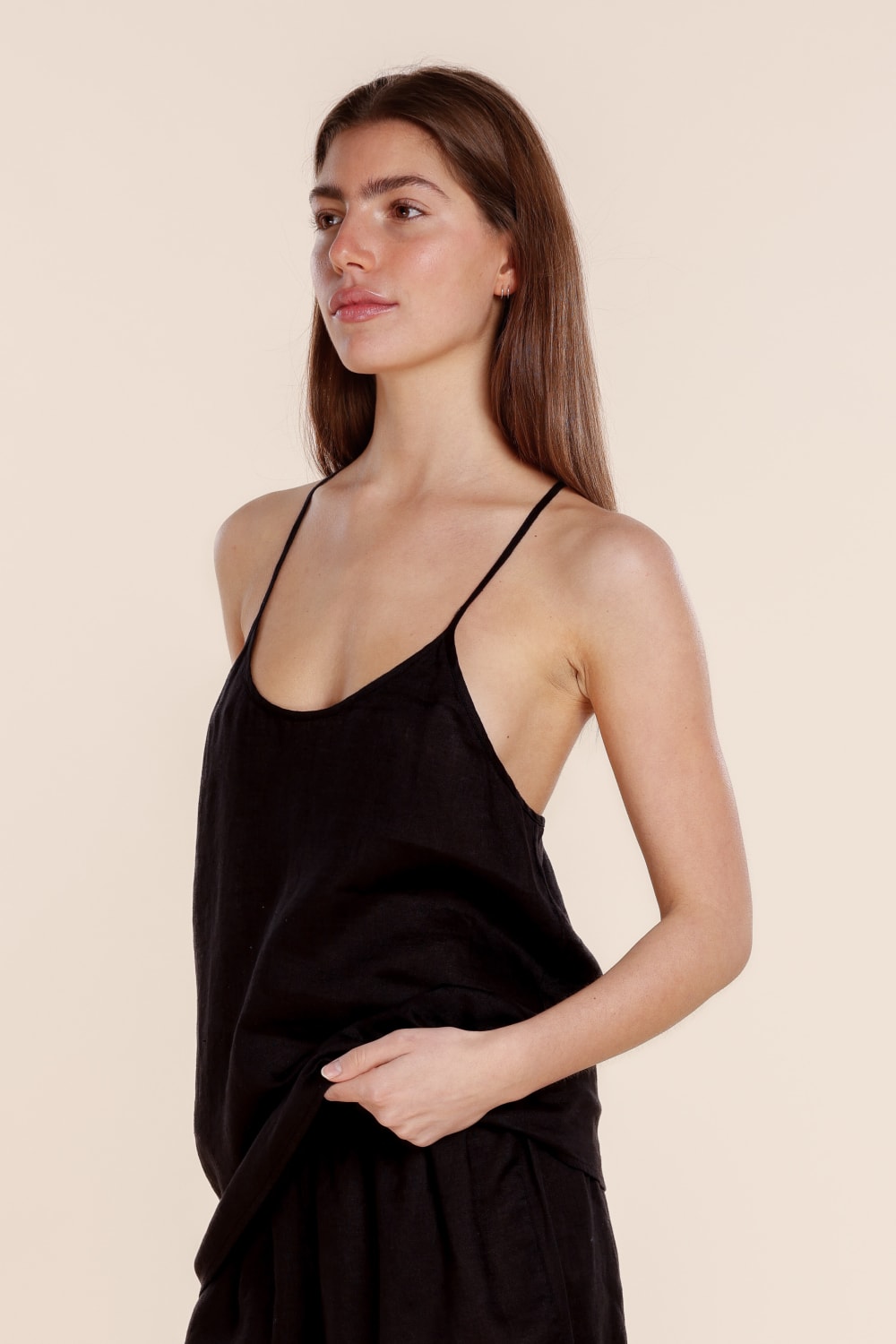 Woman wearing a black slip dress against a beige background