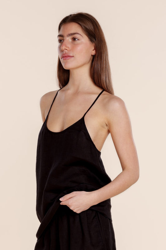 Woman wearing a black slip dress against a beige background