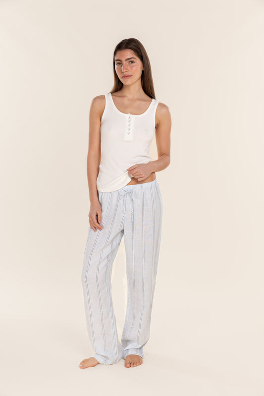 Woman wearing a white tank top and striped pants on a beige background