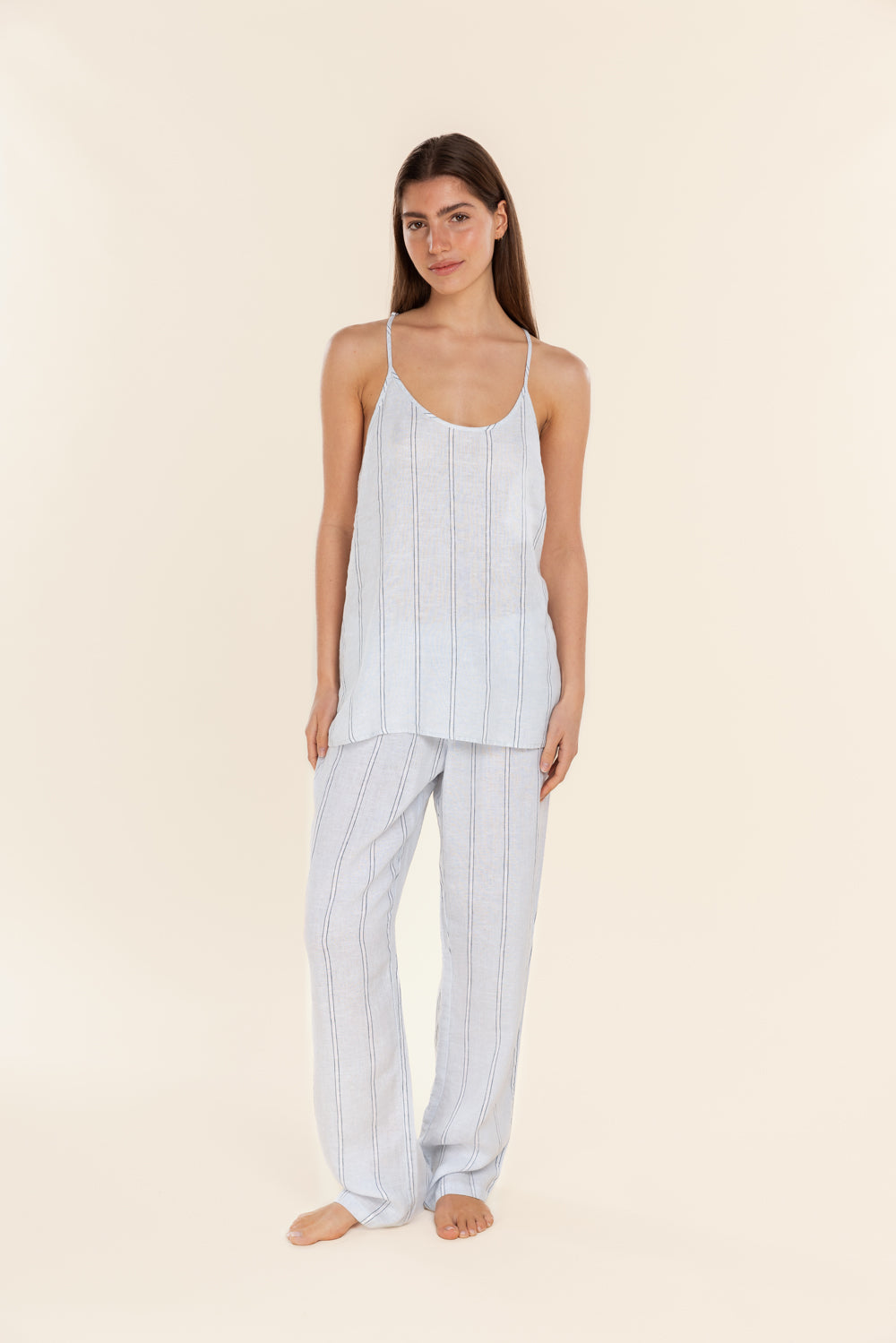 Woman wearing a light blue striped pajama set on a beige background