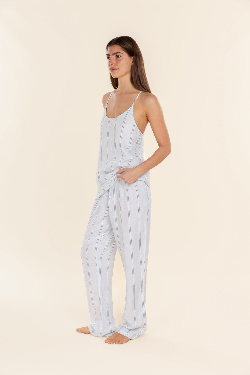 Woman wearing a light blue striped pajama set on a beige background