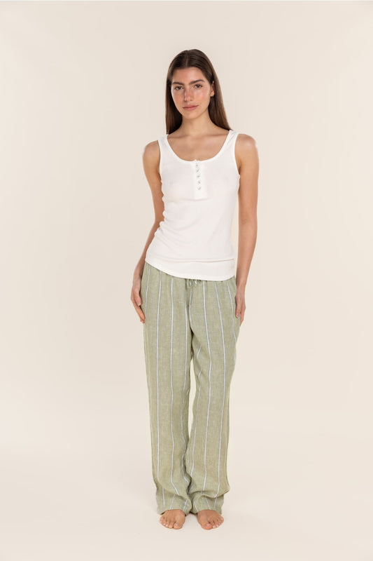 Woman wearing a white tank top and green striped pants on a beige background